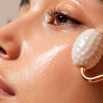 A woman practicing minimal skincare using a jade face roller for a natural glow and healthy skin routine in 2026.